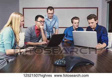 Young millennial business professionals working together in a conference room in a high tech modern business; Sherwood Park, Alberta, Canada View Large Photo Image Stock Photograph - Young millennial business professionals working together in a conference room in a high tech modern business; Sherwood Park, Alberta, Canada. Fotosearch
