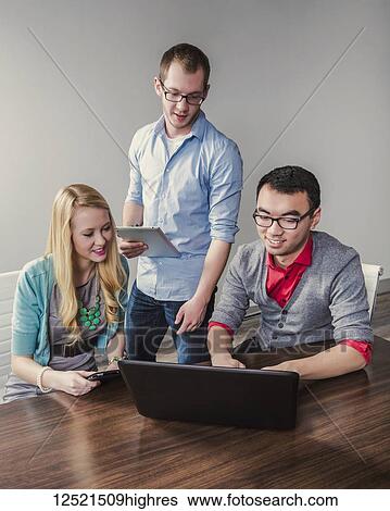 Stock Photograph - Young millennial business professionals working together in a conference room in a high tech modern business; Sherwood Park, Alberta, Canada. Fotosearch