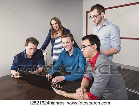 Young millennial business professionals working together in a conference room in a high tech modern business; Sherwood Park, Alberta, Canada View Large Photo Image Stock Photograph - Young millennial business professionals working together in a conference room in a high tech modern business; Sherwood Park, Alberta, Canada. Fotosearch