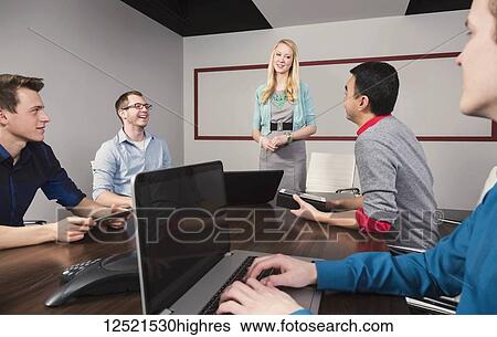 Young millennial businesswoman giving a presentation to other business professionals working in a conference room in a modern place of business; Sherwood Park, Alberta, Canada View Large Photo Image Stock Photograph - Young millennial businesswoman giving a presentation to other business professionals working in a conference room in a modern place of business; Sherwood Park, Alberta, Canada. Fotosearch