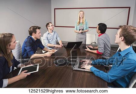 Stock Photograph - Young millennial businesswoman speaking to a group of young professionals in a conference room in a place of business; Sherwood Park, Alberta, Canada. Fotosearch