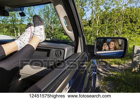 Young woman using her cell phone in a passenger seat in a vehicle; Edmonton, Alberta, Canada View Large Photo Image Stock Photograph - Young woman using her cell phone in a passenger seat in a vehicle; Edmonton, Alberta, Canada. Fotosearch