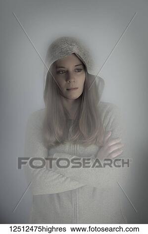 Young woman wearing a sweatshirt with hood up, standing with arms crossed in a haze; Connecticut, United States of America View Large Photo Image Stock Photograph - Young woman wearing a sweatshirt with hood up, standing with arms crossed in a haze; Connecticut, United States of America. Fotosearch