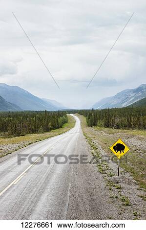 Stock Image - A Bison crossing sign along the Alaska Highway north of Muncho Lake, Muncho Lake Provincial Park, British Columbia, Canada, Summer. Fotosearch