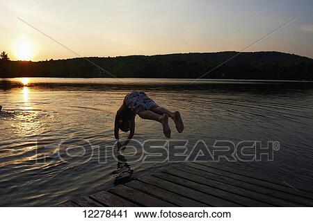 Stock Image - Boy diving into a lake at sunset; Lac des Neiges, Quebec, Canada. Fotosearch
