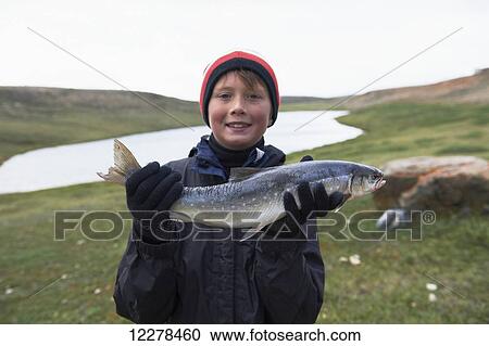 Stock Image - Boy holds fresh caught Arctic Char near Cambridge Bay; Nunavut, Canada. Fotosearch