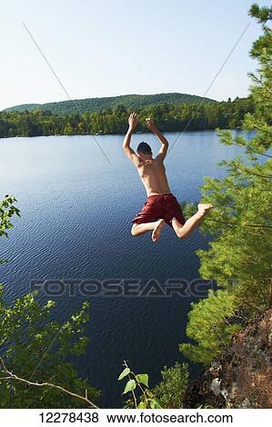Boy jumping into lake off a cliff; Lac des Neiges, Quebec, Canada View Large Photo Image Stock Photo - Boy jumping into lake off a cliff; Lac des Neiges, Quebec, Canada. Fotosearch