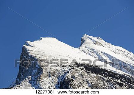 Close up of a snow covered mountain peak and blue sky; Banff, Alberta, Canada View Large Photo Image Stock Image - Close up of a snow covered mountain peak and blue sky; Banff, Alberta, Canada. Fotosearch