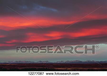Dramatic colourful sky at sunrise with mountain range in the distance; Calgary, Alberta, Canada View Large Photo Image Stock Photo - Dramatic colourful sky at sunrise with mountain range in the distance; Calgary, Alberta, Canada. Fotosearch