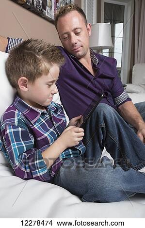 Picture - Father and son spending time together looking at tablet; Spruce Grove, Alberta, Canada. Fotosearch