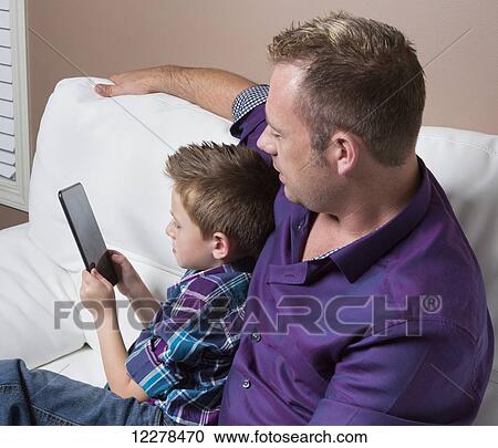 Father and son spending time together looking at tablet; Spruce Grove, Alberta, Canada View Large Photo Image Stock Image - Father and son spending time together looking at tablet; Spruce Grove, Alberta, Canada. Fotosearch