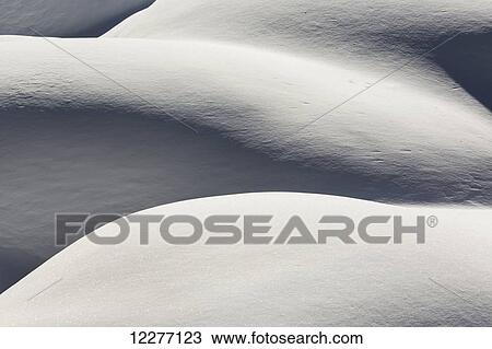 Stock Image - Fresh snow covered mounds with light and shadow creating interesting patterns; Banff, Alberta, Canada. Fotosearch
