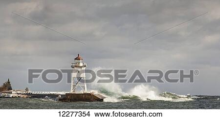Picture - Large waves splashing up to a lighthouse; Grand Marais, Minnesota, United States of America. Fotosearch
