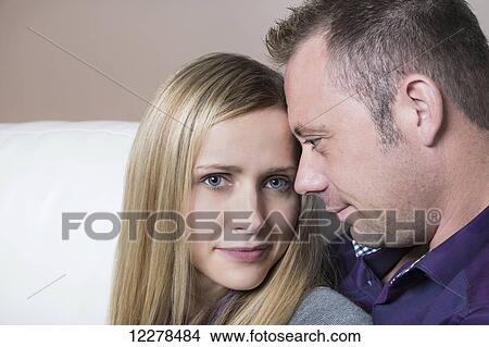 Picture - Married couple cuddling on the couch, wife has a spinal cord injury and is a paraplegic; Spruce Grove, Alberta, Canada. Fotosearch