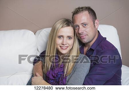 Stock Image - Married couple cuddling on the couch, wife has a spinal cord injury and is a paraplegic; Spruce Grove, Alberta, Canada. Fotosearch