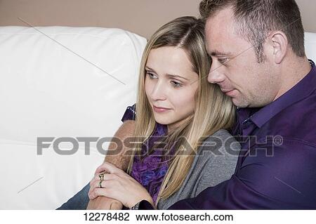 Stock Image - Married couple cuddling on the couch, wife has a spinal cord injury and is a paraplegic; Spruce Grove, Alberta, Canada. Fotosearch