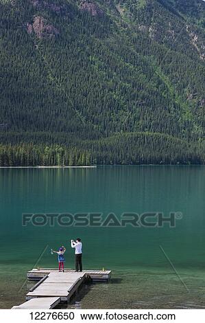 Stock Image - Mother and daughter on a dock at Muncho Lake Provincial Park, British Columbia, Canada, Summer. Fotosearch