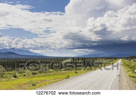 Stock Image - Scenic view of the Alaska Highway near Whitehorse with rain clouds in the distance, Yukon Territory, Canada, Summer. Fotosearch