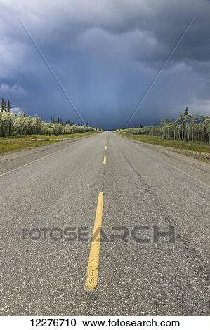 Stock Image - Scenic view of the Alaska Highway near Whitehorse with rain clouds in the distance, Yukon Territory, Canada, Summer. Fotosearch