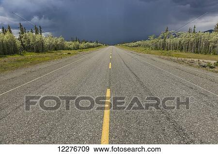 Stock Photo - Scenic view of the Alaska Highway near Whitehorse with rain clouds in the distance, Yukon Territory, Canada, Summer. Fotosearch