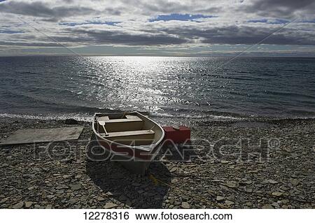 Stock Photograph - Small boat beached on the shore of the Arctic Ocean; Cambridge Bay, Nunavut, Canada. Fotosearch