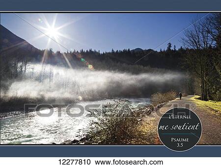 Stock Image - Sun rising over the Chilliwack River with French scripture; Chilliwack, British Columbia, Canada. Fotosearch