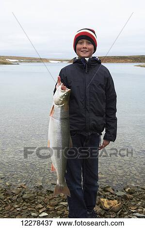 Teenage boy holding Arctic Char on the shore of the bay, near Cambridge Bay; Nunavut, Canada View Large Photo Image Stock Photo - Teenage boy holding Arctic Char on the shore of the bay, near Cambridge Bay; Nunavut, Canada. Fotosearch