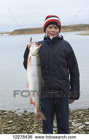 Teenage boy holding Arctic Char on the shore of the bay, near Cambridge Bay; Nunavut, Canada View Large Photo Image Stock Photograph - Teenage boy holding Arctic Char on the shore of the bay, near Cambridge Bay; Nunavut, Canada. Fotosearch