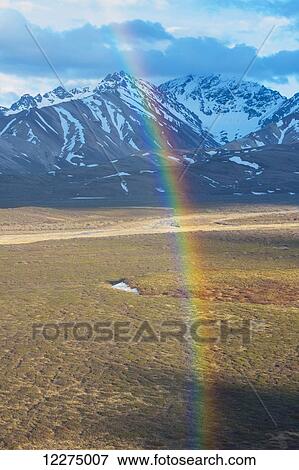 Stock Photo - View of a rainbow at Polychrome Pass with the Alaska Range in the background, Denali National park, Interior Alaska, Spring. Fotosearch