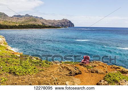 Stock Photography - View of a red stuffed arm chair placed on a cliff edge; Poipu, Kauai, Hawaii, United States of America. Fotosearch