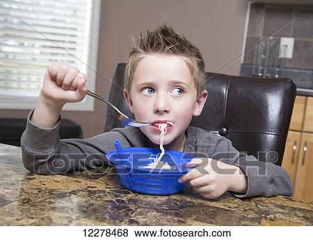 Young boy eating noodles at the kitchen table; Spruce Grove, Alberta, Canada View Large Photo Image Stock Photo - Young boy eating noodles at the kitchen table; Spruce Grove, Alberta, Canada. Fotosearch