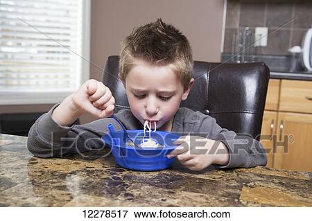 Stock Photo - Young boy eating noodles at the kitchen table; Spruce Grove, Alberta, Canada. Fotosearch