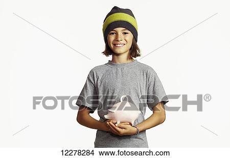 Picture - Young boy holding ceramic piggy bank; Montreal, Quebec, Canada. Fotosearch