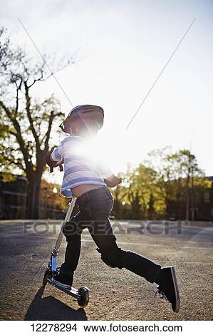 Young boy riding a scooter; Montreal, Quebec, Canada View Large Photo Image Picture - Young boy riding a scooter; Montreal, Quebec, Canada. Fotosearch