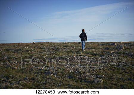 Stock Image - Young boy walking on the tundra, near Cambridge Bay; Nunavut, Canada. Fotosearch