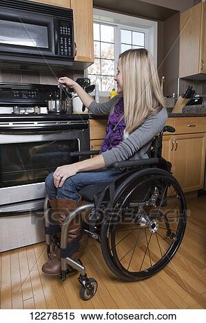 Stock Photography - Young disabled woman cooking in her kitchen; Spruce Grove, Alberta, Canada. Fotosearch