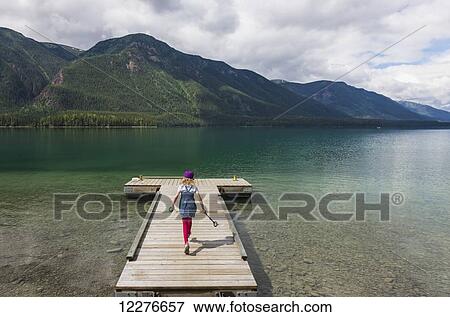 Stock Photo - Young girl on a dock at Muncho Lake Provincial Park, British Columbia, Canada, Summer. Fotosearch