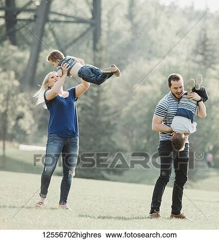 Stock Photograph - A family with young children playing in a park; Edmonton, Alberta, Canada. Fotosearch