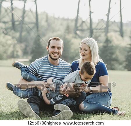 Stock Photograph - A family with young children playing in a park; Edmonton, Alberta, Canada. Fotosearch