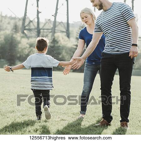 Stock Photograph - A family with young son playing in a park; Edmonton, Alberta, Canada. Fotosearch