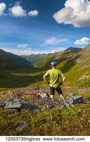 A man pausing for a rest while riding his mountain bike on the Palmer Valley Road near Hope, Alaska on a sunny summer day in South-central Alaska; Alaska, United States of America View Large Photo Image Stock Photograph - A man pausing for a rest while riding his mountain bike on the Palmer Valley Road near Hope, Alaska on a sunny summer day in South-central Alaska; Alaska, United States of America. Fotosearch