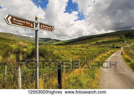 A sign for hiking trails, Bluestack Way, and a road leading through a hilly landscape; County Donegal, Ireland View Large Photo Image Stock Photograph - A sign for hiking trails, Bluestack Way, and a road leading through a hilly landscape; County Donegal, Ireland. Fotosearch