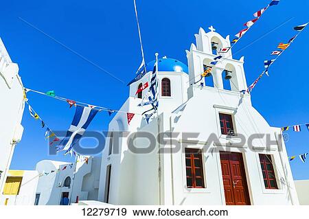 A traditional greek orthodox church with world flags adorning in every direction for celebration and the Greek flag; Oia, Santorini, Greece View Large Photo Image Stock Photo - A traditional greek orthodox church with world flags adorning in every direction for celebration and the Greek flag; Oia, Santorini, Greece. Fotosearch