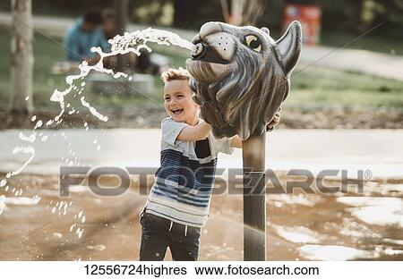 Stock Photograph - A young boy at a spray park; Edmonton, Alberta, Canada. Fotosearch