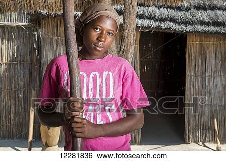Stock Photograph - African woman holding a pestle in Sexaxa Village; Maun, Botswana. Fotosearch