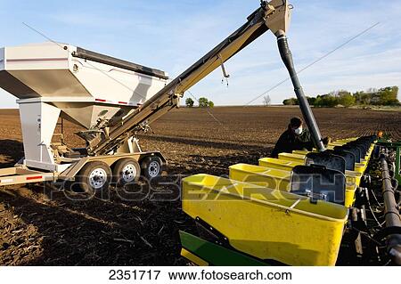 Stock Photo - Agriculture - A farmer prepares for corn planting operations by loading his planter hoppers with corn seed from a seed tender / Minnesota, USA.. Fotosearch