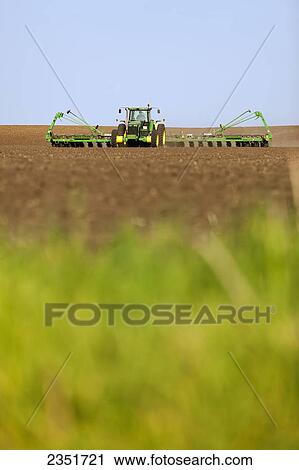 Stock Image - Agriculture - A John Deere tractor and 24-row planter planting corn in a conventionally tilled field / Minnesota, USA.. Fotosearch