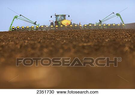 Stock Image - Agriculture - A John Deere tractor and 24-row planter planting corn in a conventionally tilled field / Minnesota, USA.. Fotosearch