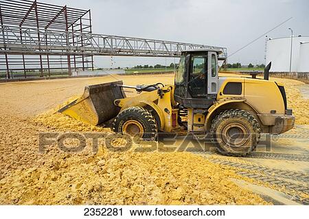 Stock Image - Agriculture - A wheel loader moves distiller grain (DG) with solubles at an ethanol production facility. DG is the byproduct left over after ethanol production, and is increasingly used in livestock and poultry feed / Lexington, Nebraska, USA.. Fotosearch