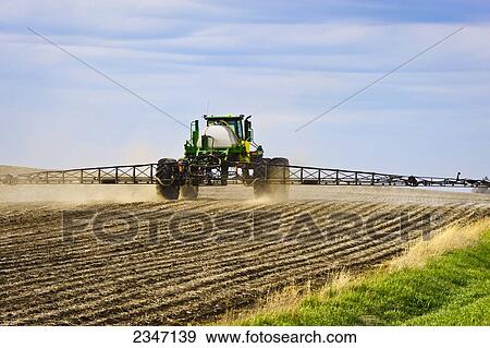 Stock Photo - Agriculture - Applying pre-emergent herbicide with a John Deere 4720 sprayer to a newly planted soybean field with the purpose of decreasing weed pressure while optimizing yield potential / Central Iowa, USA.. Fotosearch